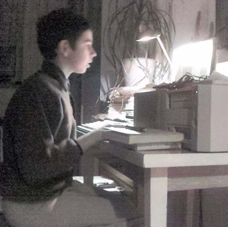 Young Konrad at an old desktop computer, lit by a desk lamp